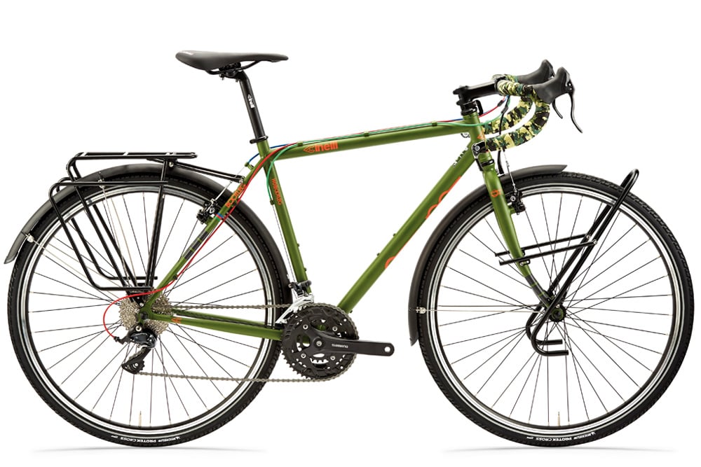 Samostatne stojaci touring bicykel s pevným zeleným rámom, športovými riadidlami, blatníkmi a nosičmi na batožinu na zadnom aj prednom kolese.
